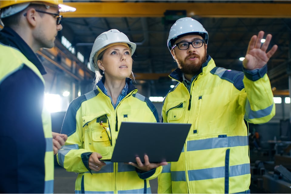 MATO engineers in safety gear discussing conveyor belt maintenance solutions inside a modern industrial facility.