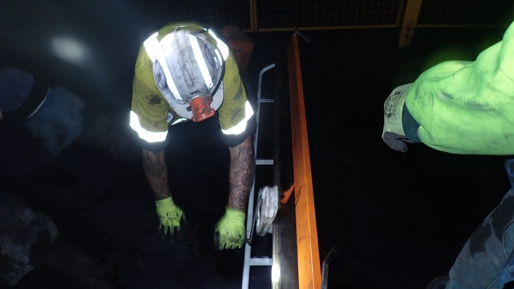 Worker handling equipment in low-light environment.